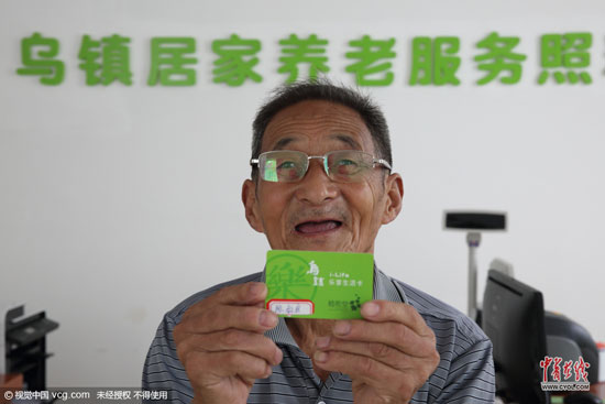 80岁的陈叔良老人在工作人员的指导下办理乐享生活卡。他凭借此卡便可享受照料中心提供的线上线下服务。 (图片作者：沈志成)