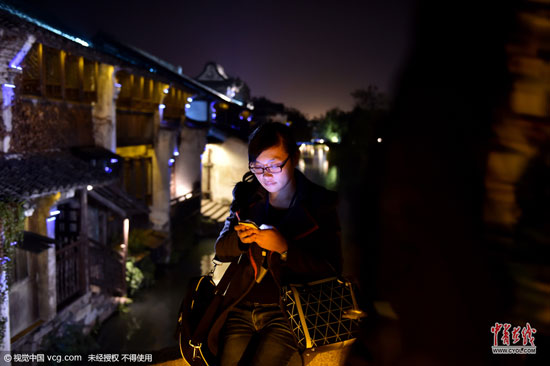 不管白天还是夜里，行走在乌镇老街上，处处可见上网的人群。(图片作者：梁臻)